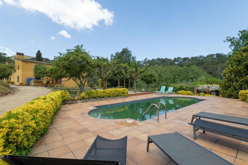 a swimming pool with two chairs and a bench at Can Marc in Dosríus