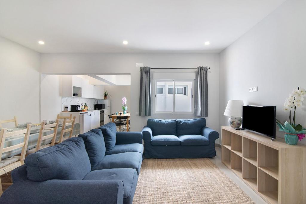 a living room with two blue couches and a kitchen at Skipper House in Loulé