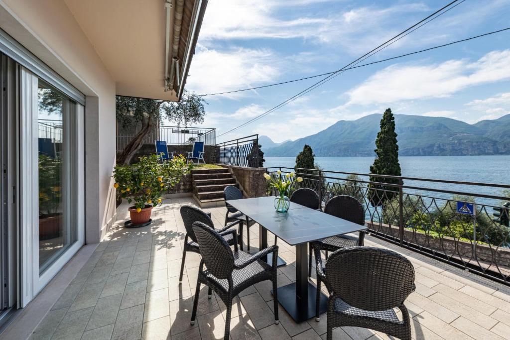 eine Terrasse mit Tisch und Stühlen und Blick aufs Wasser in der Unterkunft Cà Granda Brenzone in Brenzone sul Garda