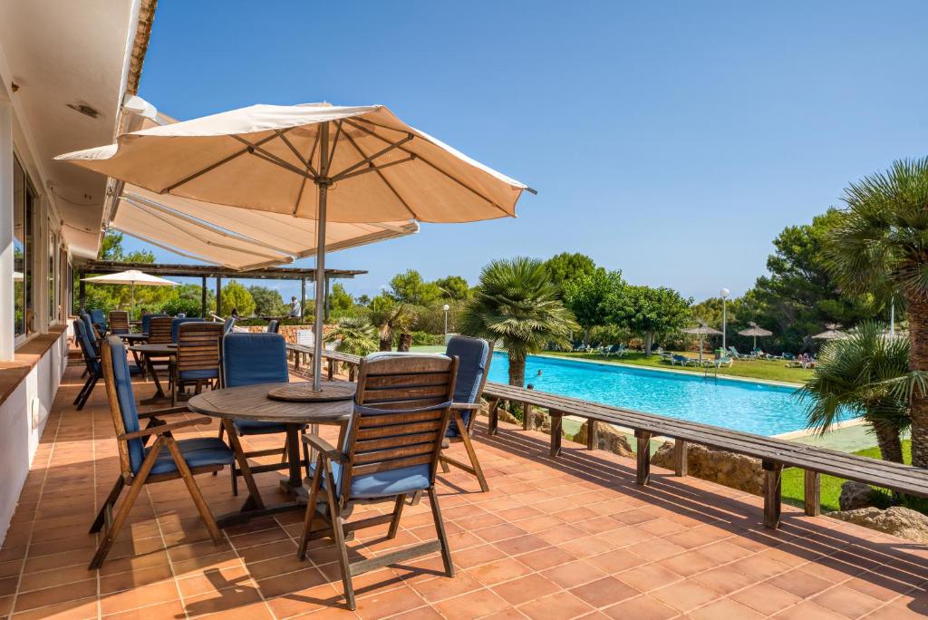 a patio with a table and chairs and an umbrella at Villa Orchidée - Coves Noves in Punta Grossa