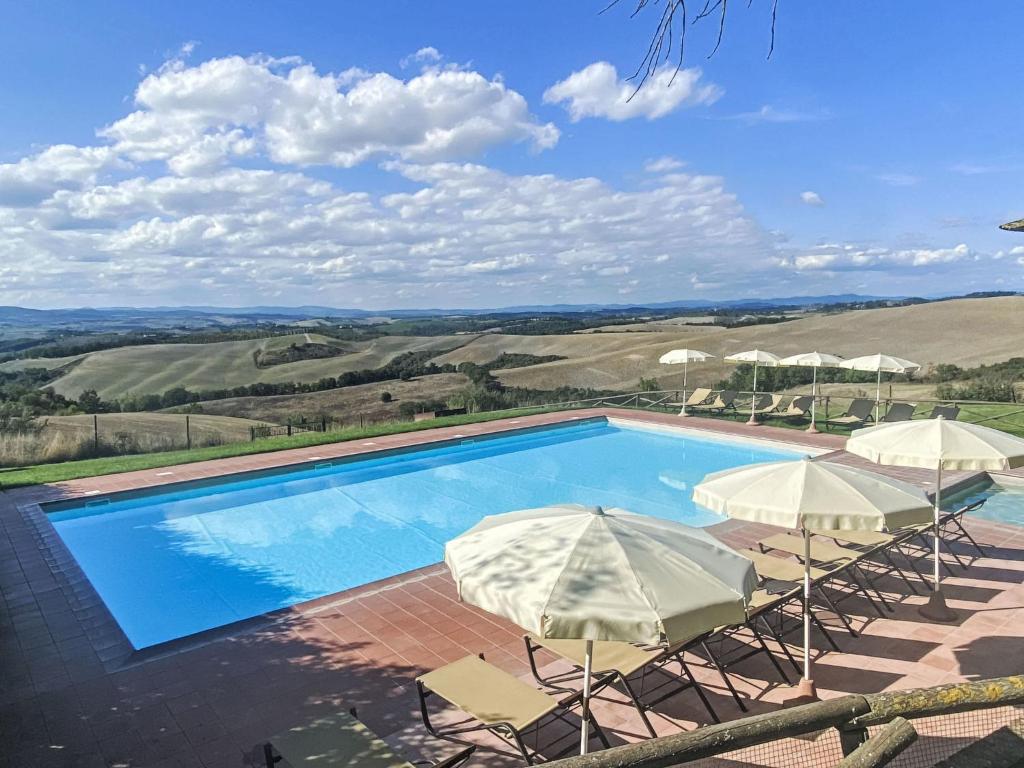 a swimming pool with two umbrellas and chairs at Apartment Torrenieri by Interhome in Vergelle