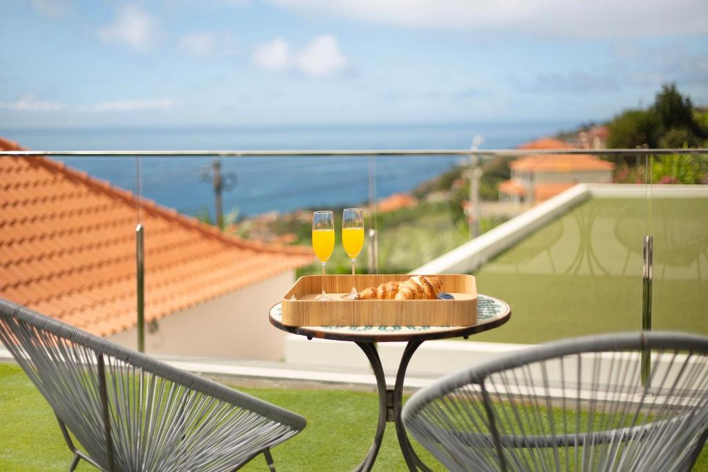 a table with two glasses of wine on a balcony at Casa Jolie in Ponta do Sol
