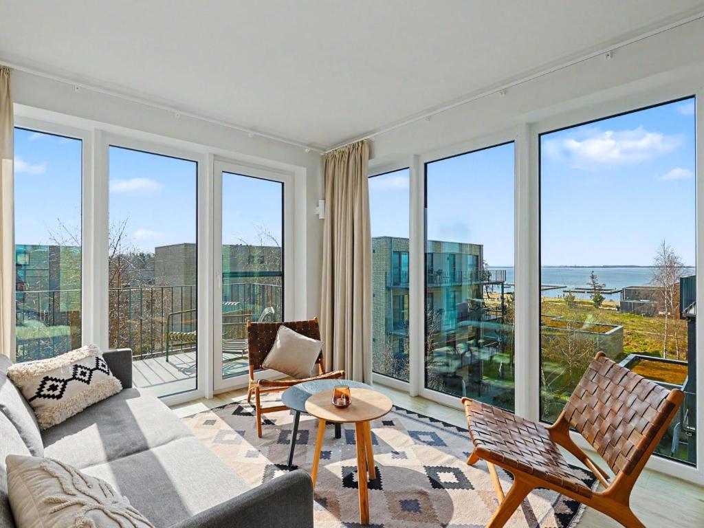 a living room with a couch and chairs and windows at Apartment Penthouse Dümmerblick - 619 by Interhome in Lembruch