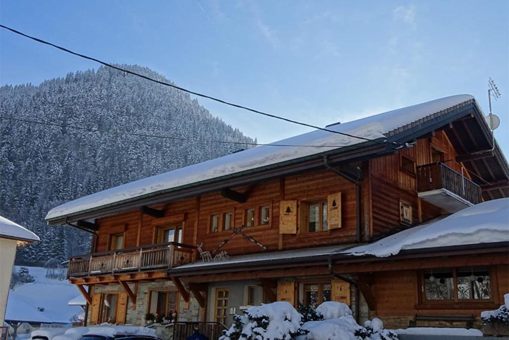 a large wooden house with snow on the roof at Appartement chalet - Le Vnipi in Abondance