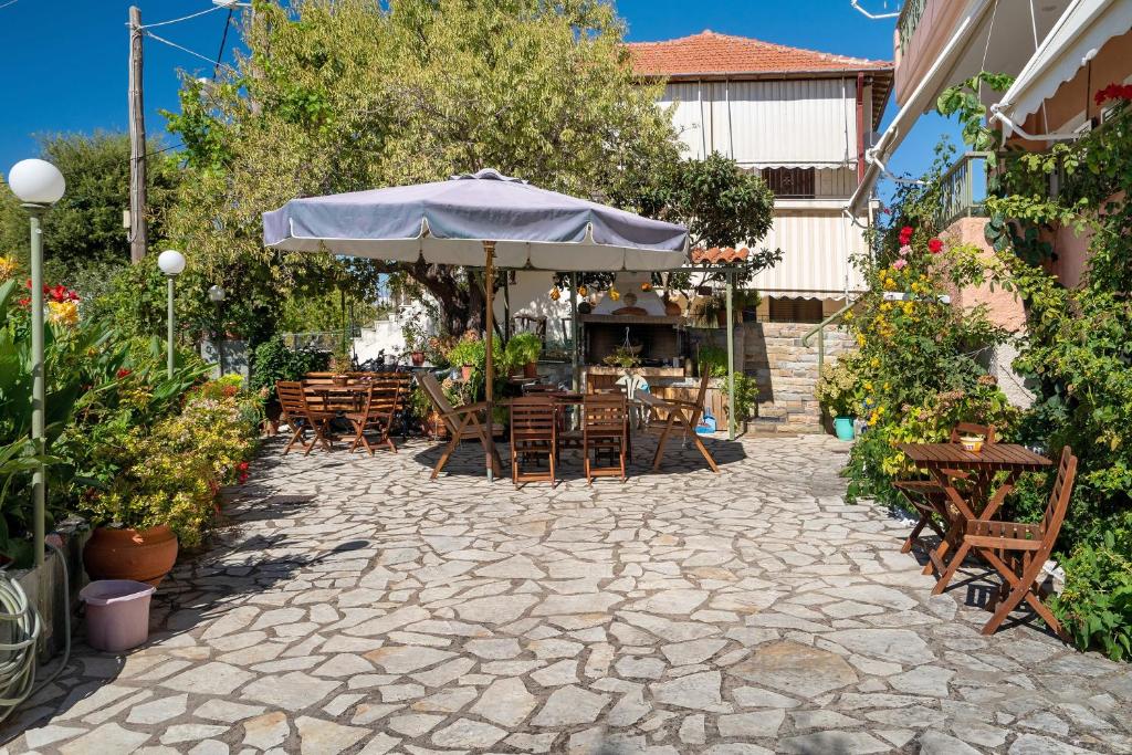 a patio with tables and chairs and an umbrella at Nontas Home 27 in Kalamitsi