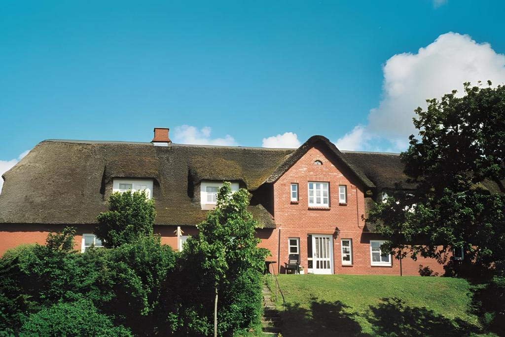 ein großes Backsteinhaus mit Reetdach in der Unterkunft Schardeichhof Meyer in Pellworm