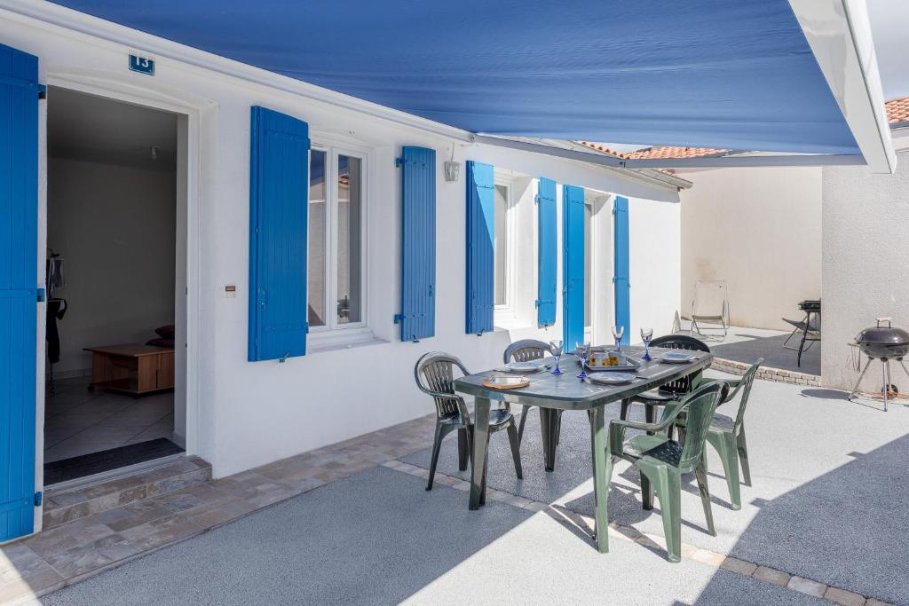 a table and chairs on a patio with blue shutters at Maison proche océan - 6 pers in Bretignolles-sur-Mer