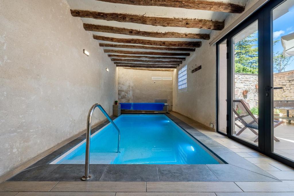 an indoor swimming pool with blue water in a room with windows at Arassa casa rural in Rocafort de Queralt