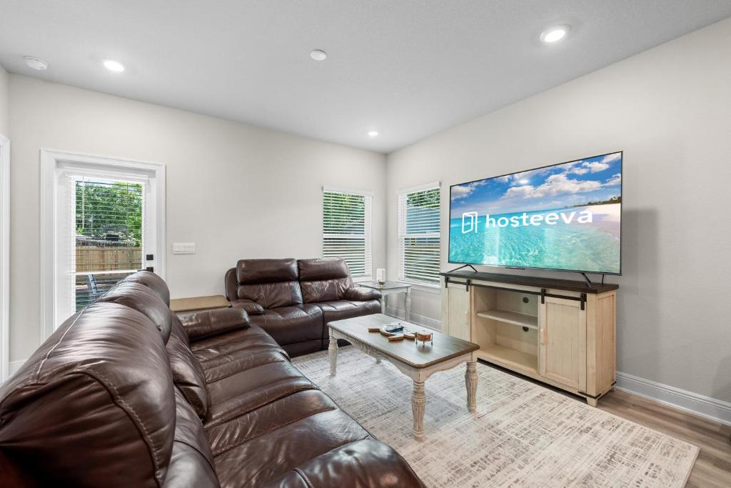 a living room with a leather couch and a flat screen tv at Marigold House in Foley