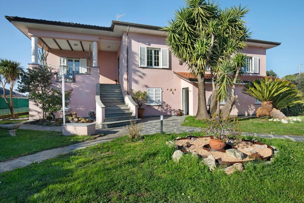 a pink house with a palm tree in the yard at Villa Lucia in Ameglia