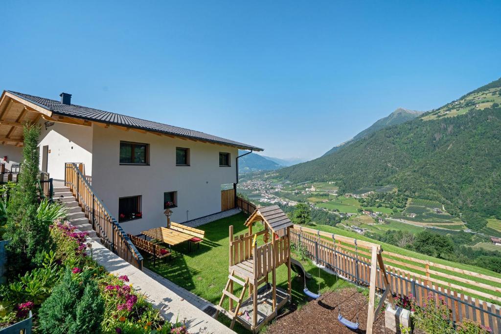 a house with a balcony with mountains in the background at Tholerhof in Schenna