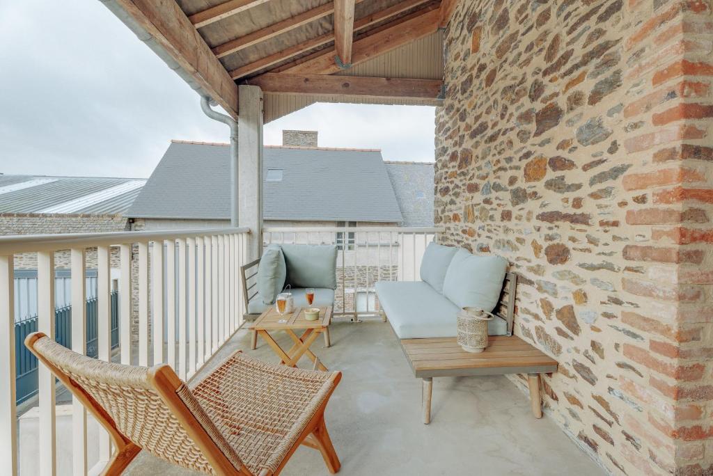 a balcony with chairs and a brick wall at Côte d'emeraude in Saint-Benoît-des-Ondes