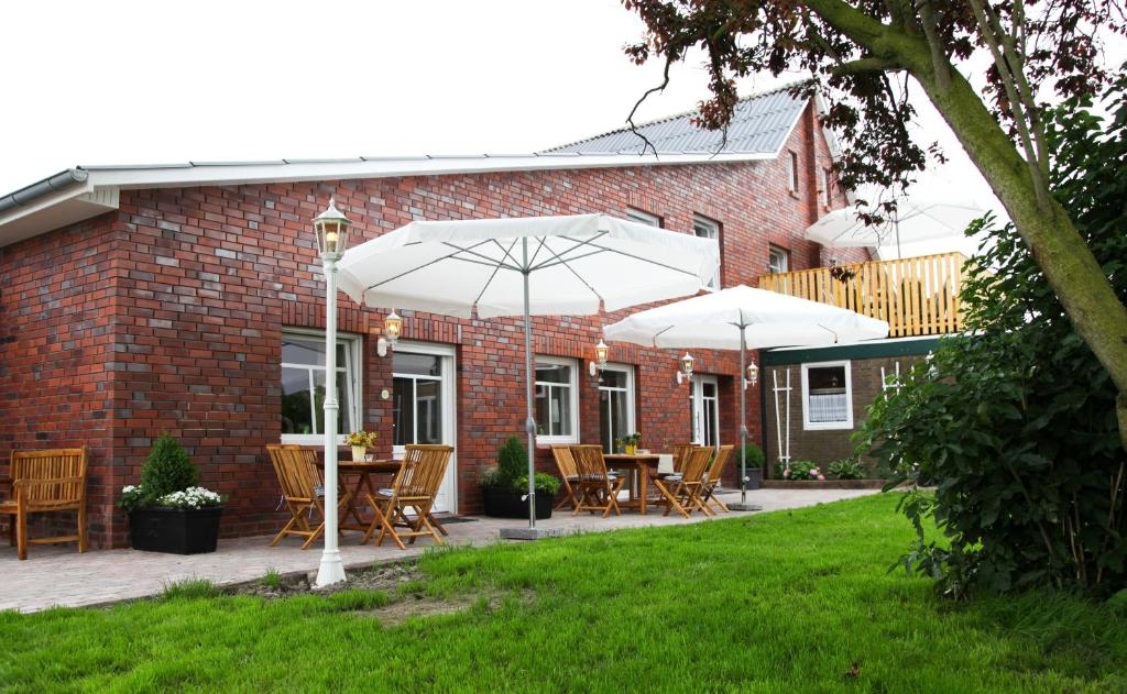a patio with tables and chairs and umbrellas at Ferienwohnung auf Ferienhof Janssen in Wangerland