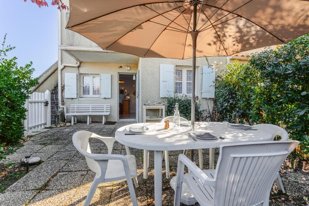a white table and chairs with an umbrella at Location Oléron, proche plage in Dolus-d'Oléron
