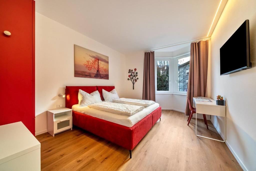 a bedroom with a red bed and a television at Central Suite Meran in Merano