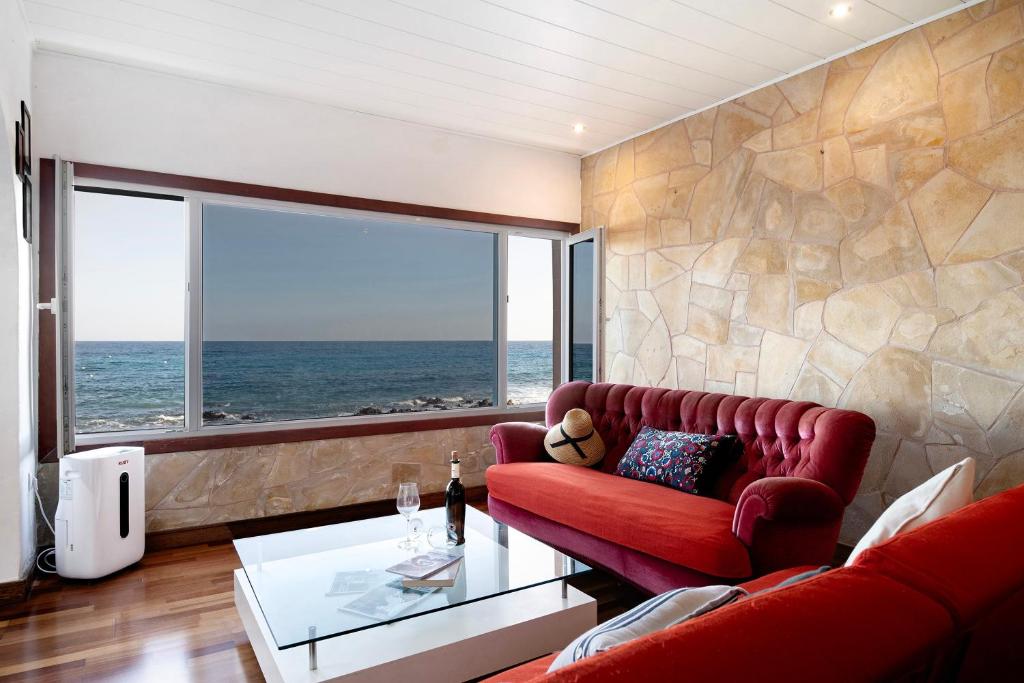 a living room with a red couch and a large window at El Mar y Tú in Arrieta