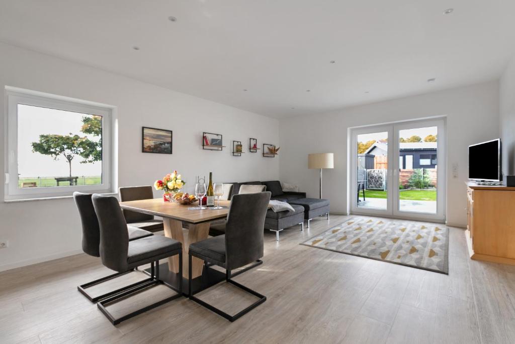 a dining room and living room with a table and chairs at Seelenwärmerstuuv in Kronprinzenkoog