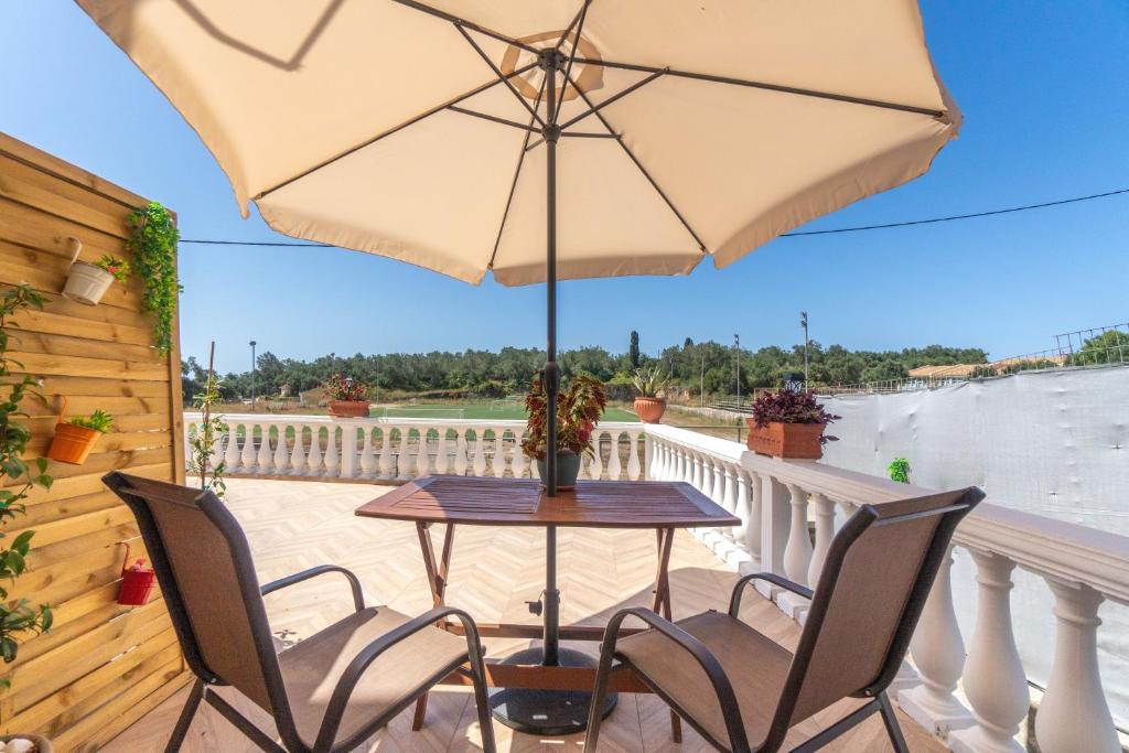 a table and chairs on a balcony with an umbrella at Maestro Apartment in Gaios