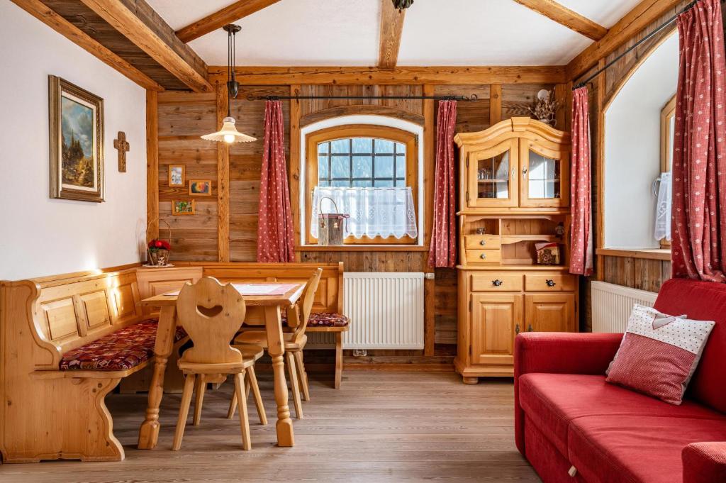 a living room with a table and a red couch at Thomasegg Hof Birke in Sarntal
