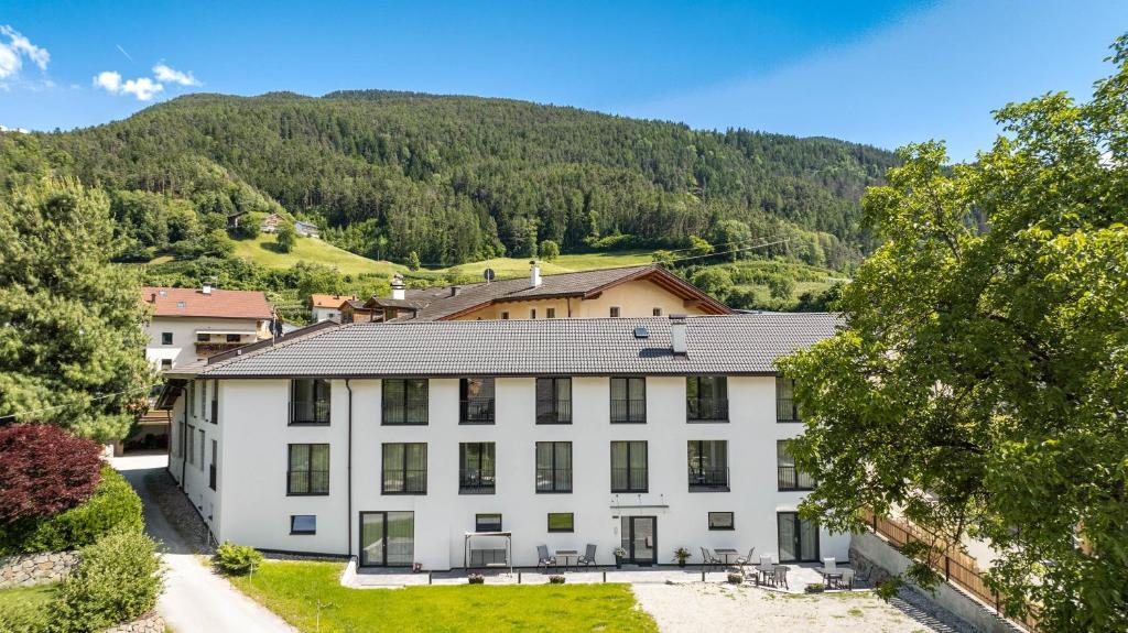 a white building with a mountain in the background at Untermoarhof Albeins in Bressanone