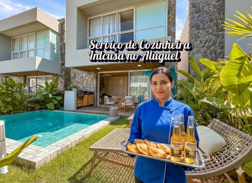 a woman holding a tray of food and drinks at Casa Verde Mar Naluum in Passo de Camarajibe