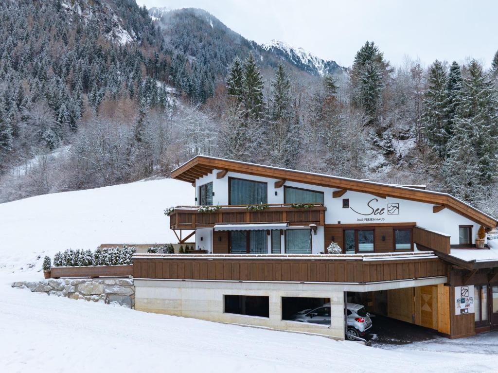 a house in the snow with mountains in the background at See das Ferienhaus in Oetz