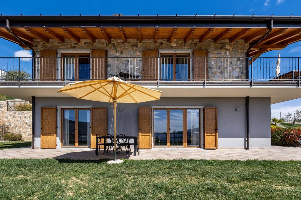 a patio with a table and a yellow umbrella at Agriturismo Bocca Nevese Abete in Tremosine Sul Garda