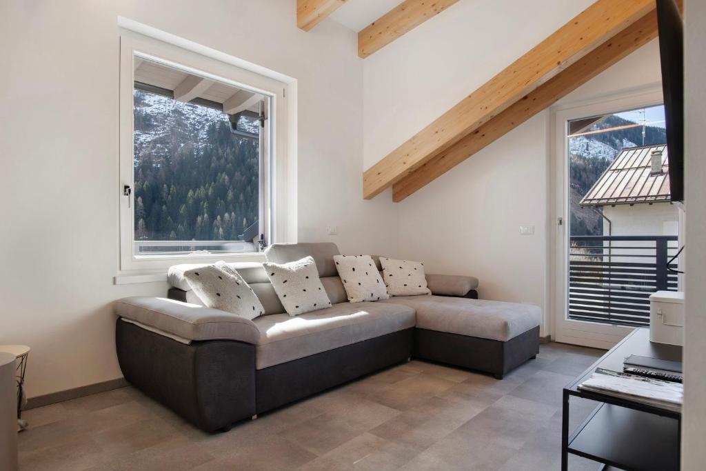 a living room with a couch and two windows at Cà Dei Nane Vermiglio in Vermiglio