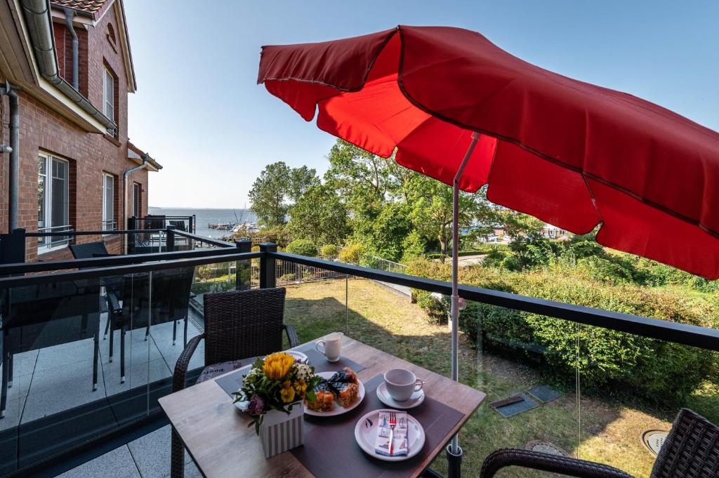 a table with a red umbrella on a balcony at Ferienwohnung Am Salzhaff B6 in Rerik