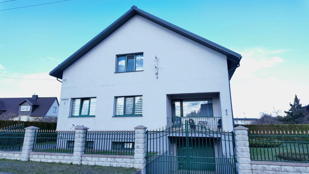 ein weißes Haus mit einem Zaun davor in der Unterkunft Bele House in Karmėlava