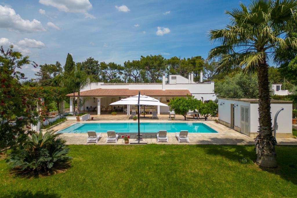 a pool with chairs and an umbrella in a yard at Tenuta Il Carretto in Monteroni di Lecce