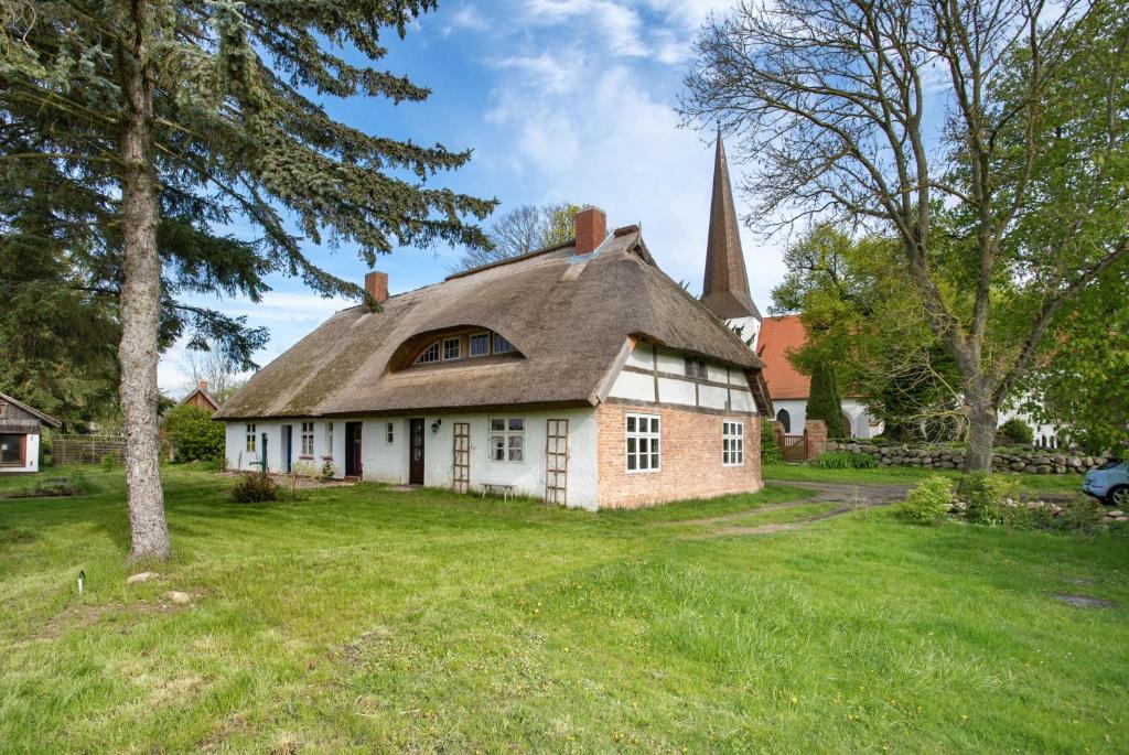 an old house with a church in a yard at Pommernhuus an de Kark in Süderholz