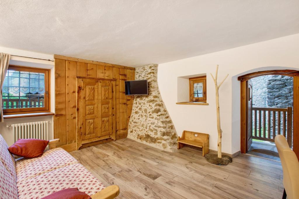 a living room with a couch and a tv on a wall at Les Cles - Genepy in Valsavarenche