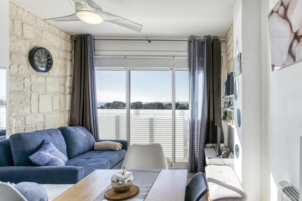 a living room with a blue couch and a large window at Ventana Loft in Empuriabrava
