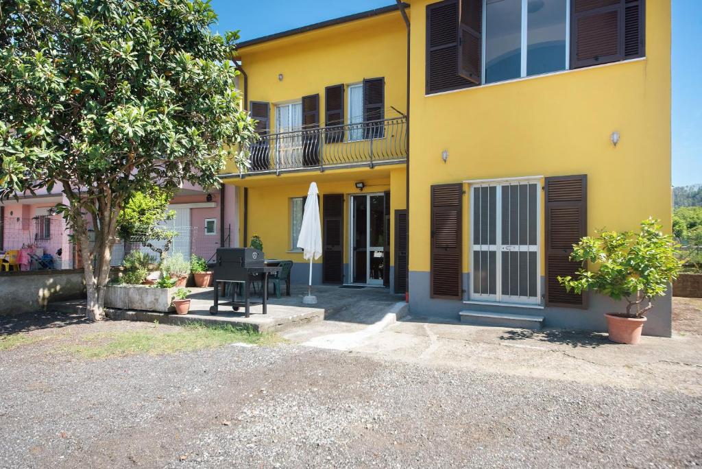 a yellow house with a table and a umbrella at Da Dri´ in Brugnato