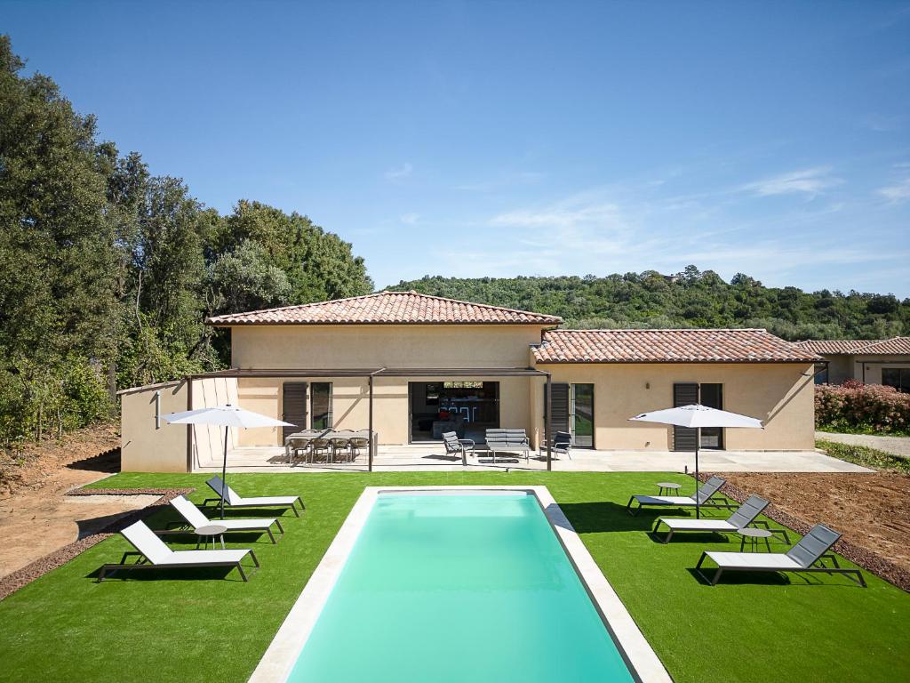 a swimming pool in front of a house with chairs and umbrellas at Villa Catherine in Ghisonaccia