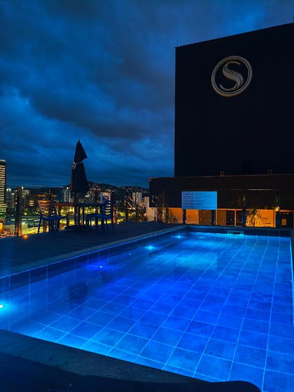 a swimming pool on top of a building at night at Brisa do Vale Loft 802 - Prox Centro e Oktoberfest - Piscina e WiFi in Blumenau