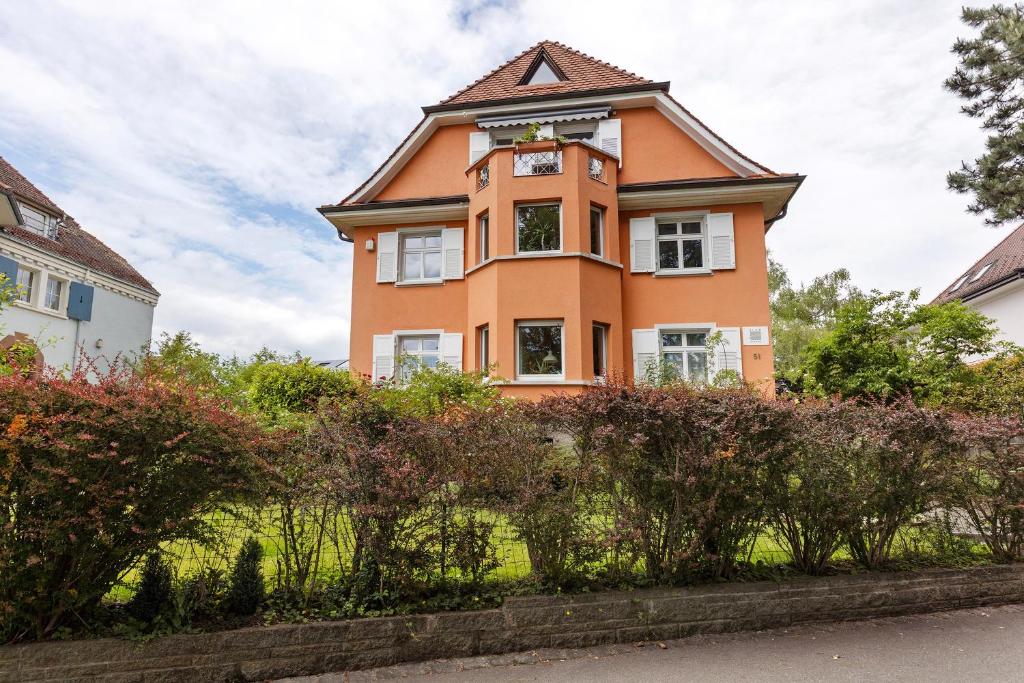 an orange house with a clock on top of it at Rotes Haus über den Weinbergen in Konstanz
