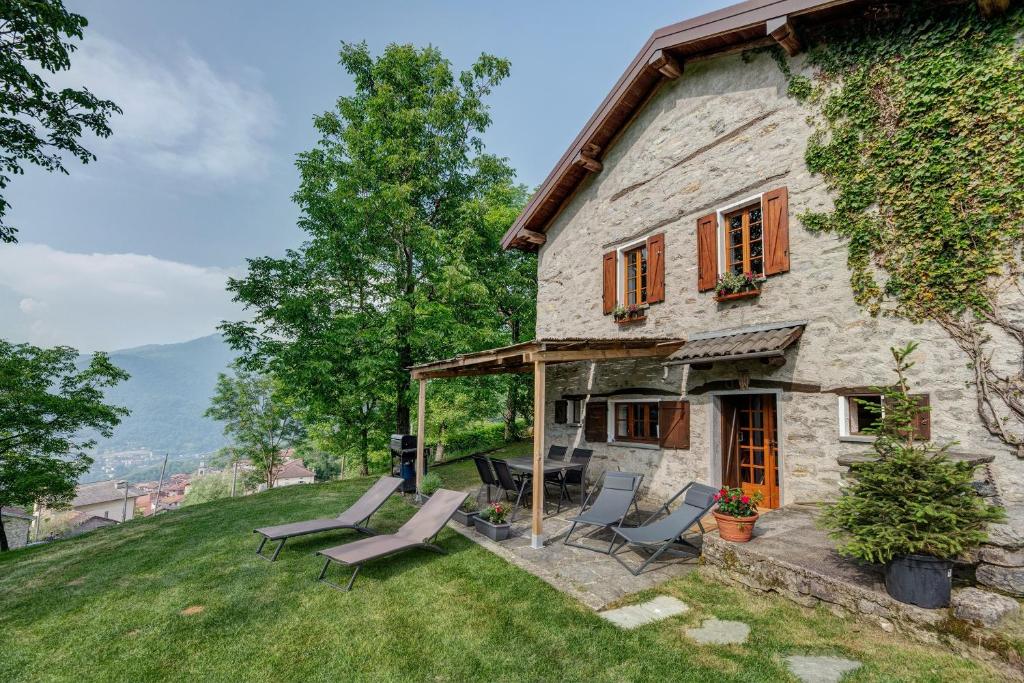 a stone house with lounge chairs on a lawn at Nini's Home in Schignano