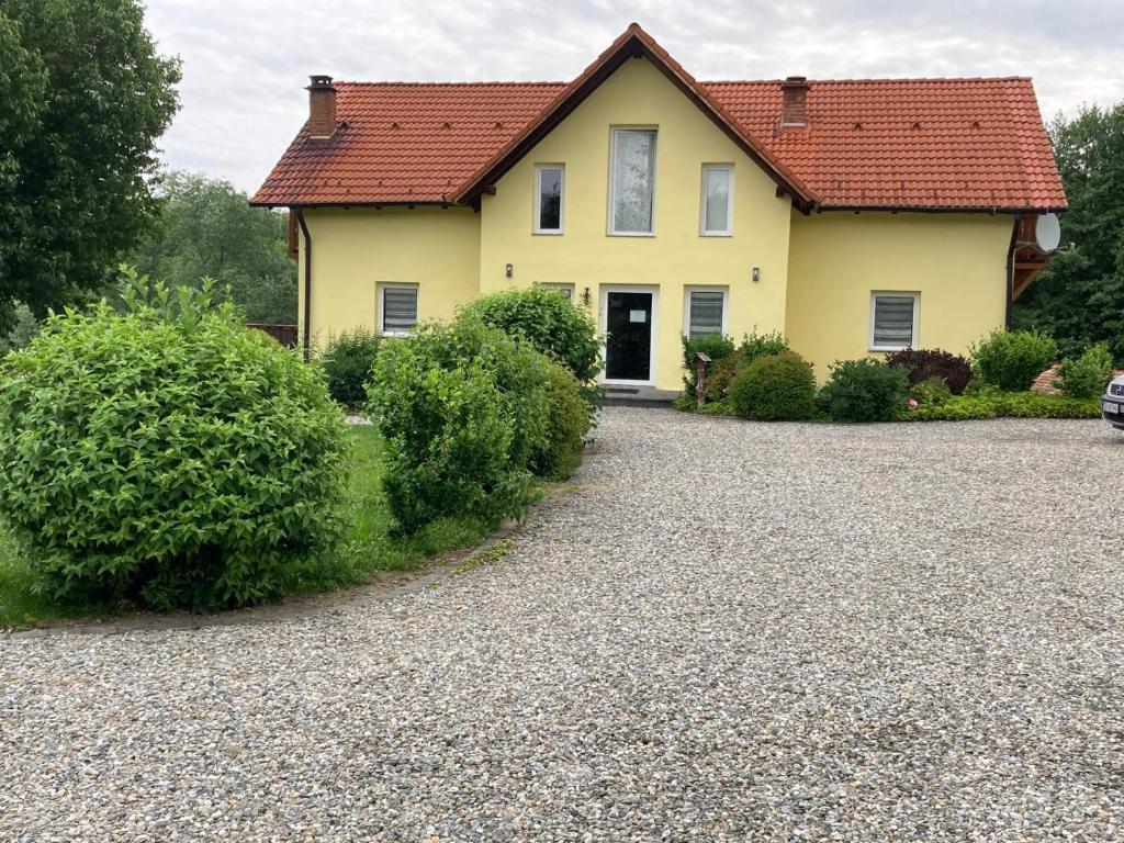 a yellow house with a gravel driveway at Pensiunea Arpasel in Arpaşu de Sus