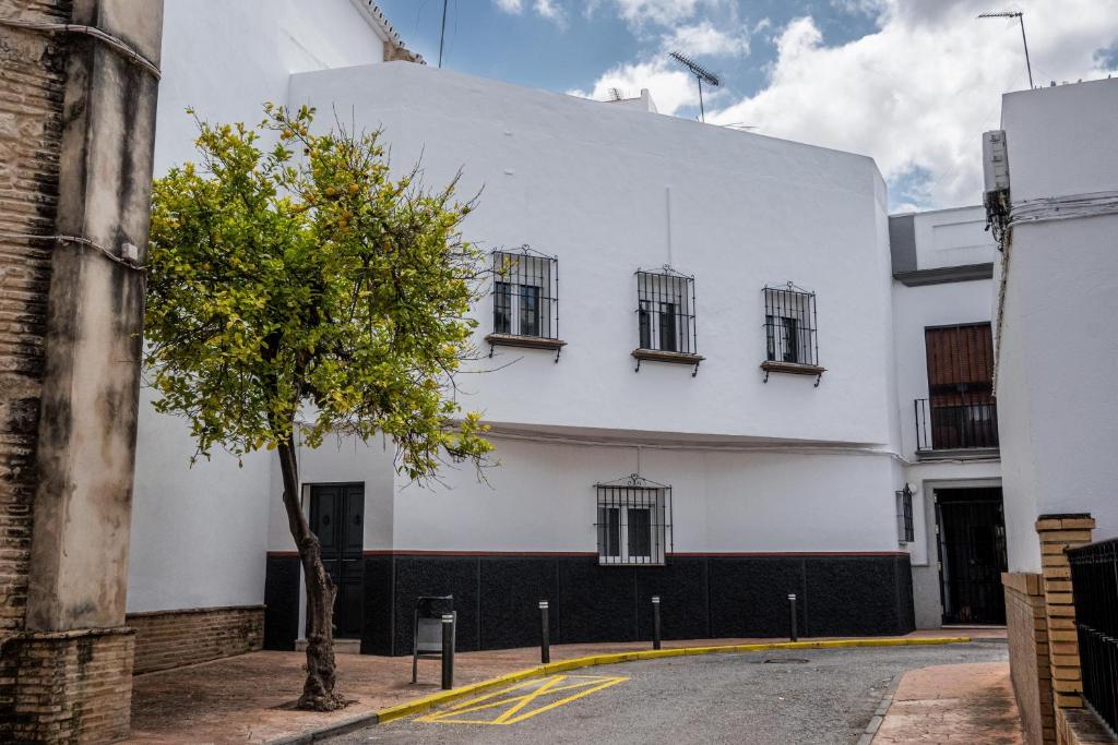 a white building with windows and a tree on a street at Santa Clara Home in Marchena