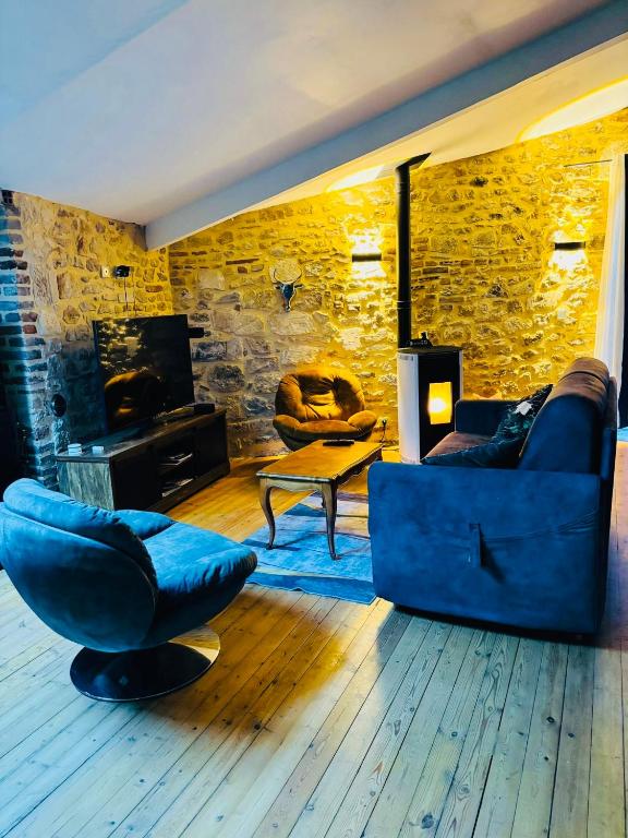 a living room with a blue couch and a stone wall at Jungle Gite in Fumel