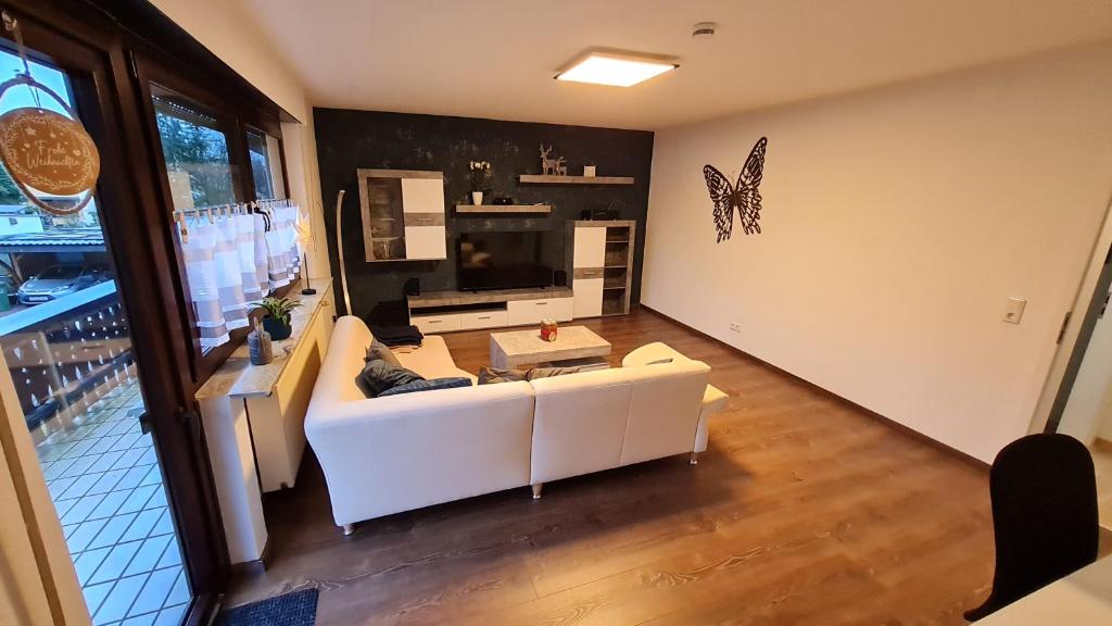 a living room with a white couch and a butterfly on the wall at Ferienwohnung Helfensteinblick in Calden