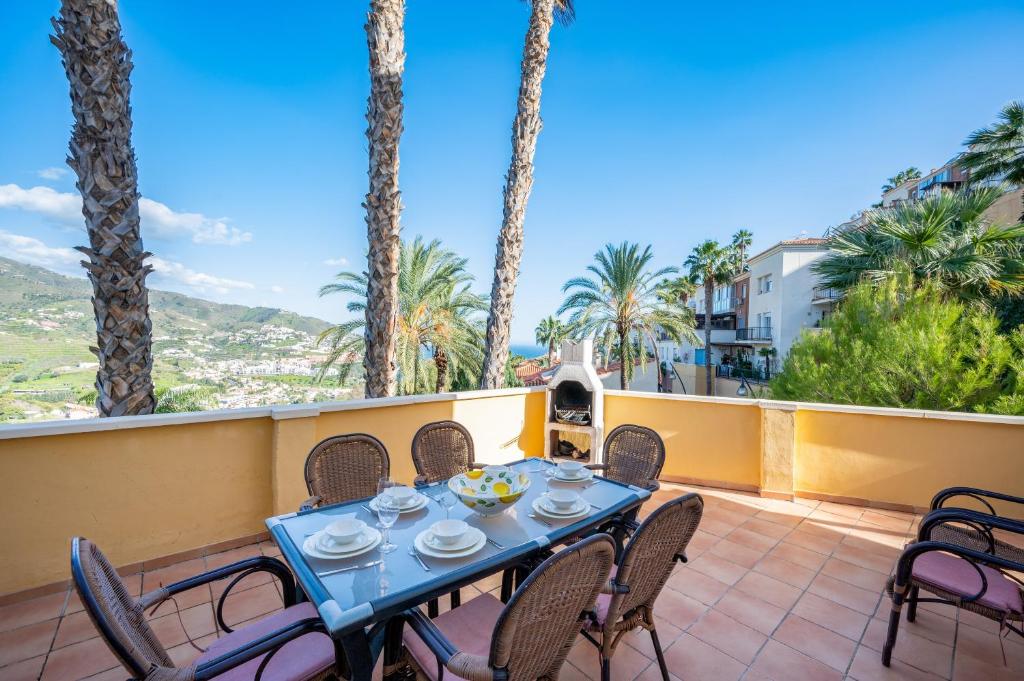 a table and chairs on a patio with palm trees at Villa Fuentes in Almuñécar