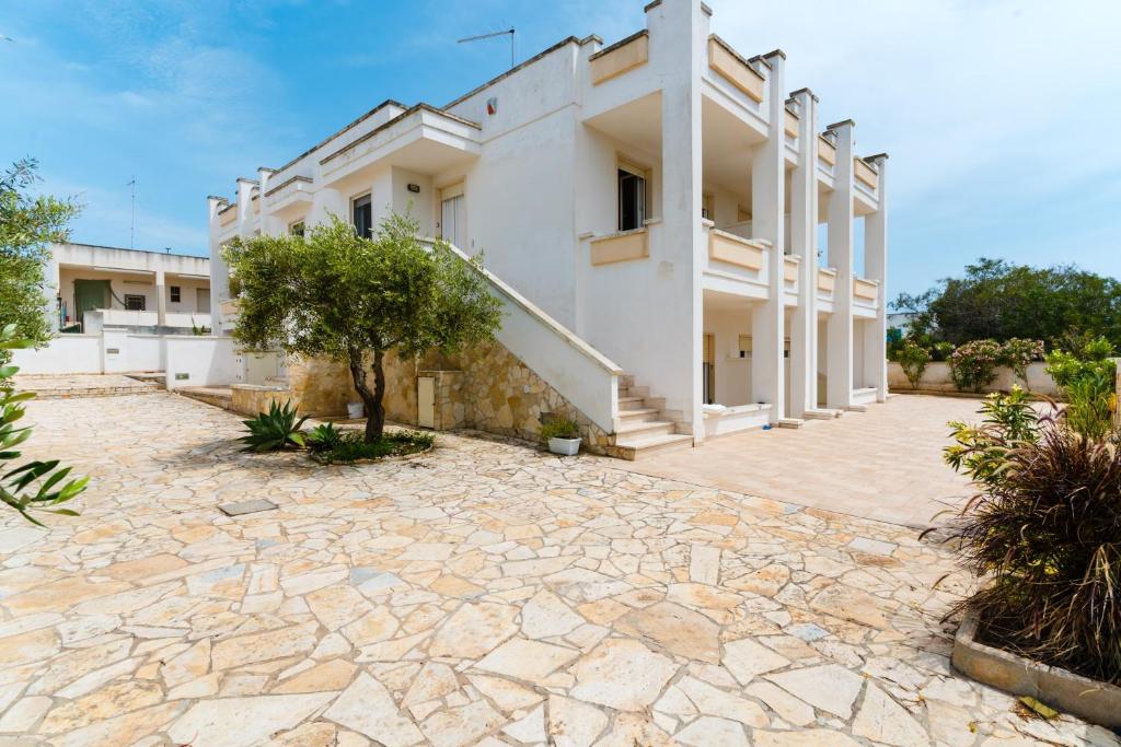 an external view of a building with a stone courtyard at Residence Punta Pizzo in Marina di Mancaversa
