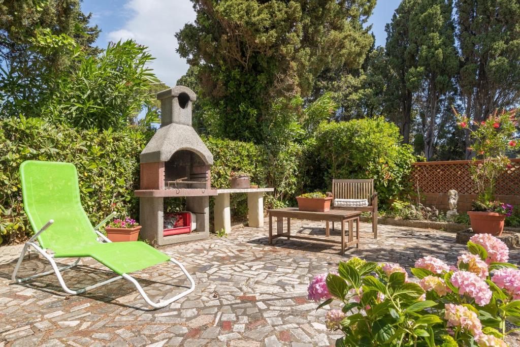 a green chair and a table and a fireplace in a garden at Castiglioncello Mare Apartment in Castiglioncello