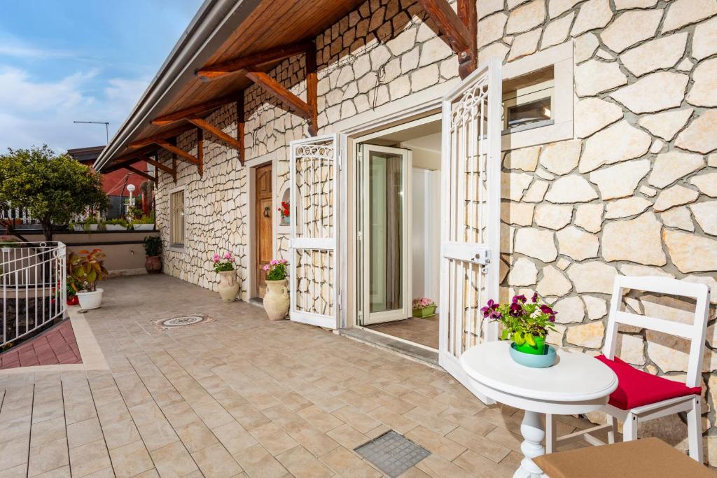 a stone house with a patio with a table and chairs at Pètra Janca in Aci SantʼAntonio