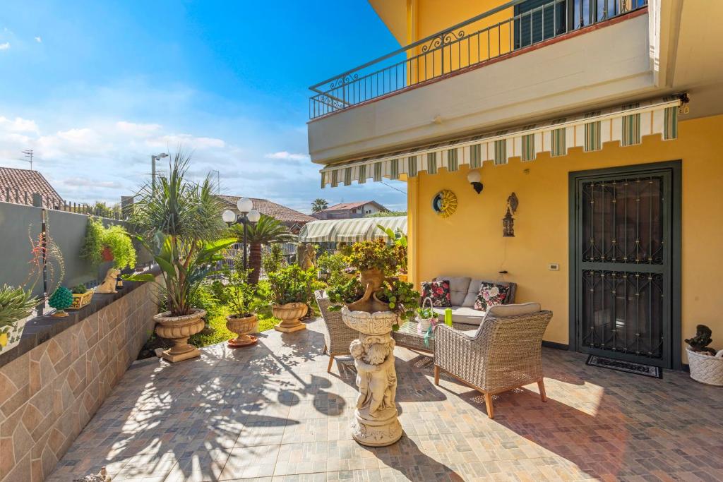 a patio with chairs and potted plants and a building at Villetta Mare e Monti in Mascali