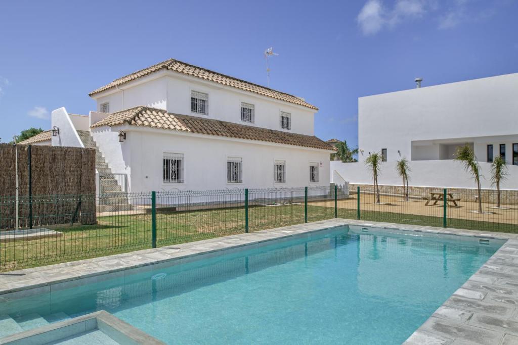 a villa with a swimming pool in front of a house at Complejo Alejandra in Conil de la Frontera