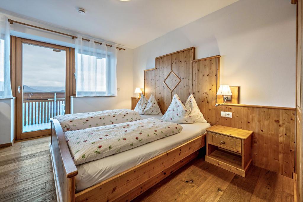 a bedroom with a bed with a wooden headboard and a window at Maurerhof Morgenrot in Maranza